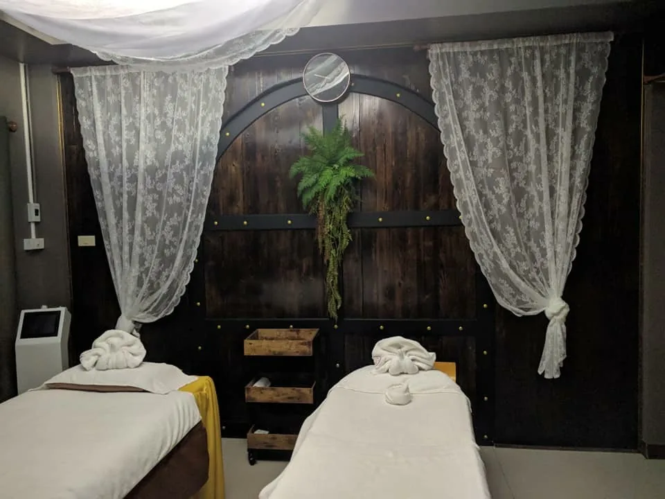 ห้องทรีตเมนต์สองเตียงปูผ้าสีทอง มีม่านลูกไม้และประตูไม้โค้ง